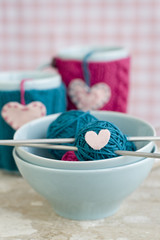 Bright balls of yarn in blue plates and heart made ​​of felt