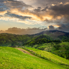 fence on hillside meadow in mountain at sunrise
