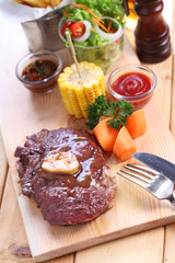 beef steak with spices on wood plate over wooden table