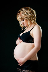Beautiful pregnant mother with tenderness looks at tummy