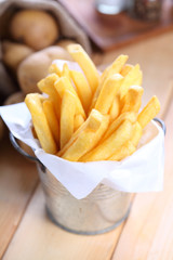 French fries in metal cup on wood table