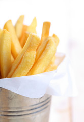 closeup of French fries in metal cup on wood table