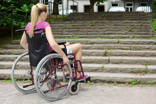 Frau im Rollstuhl vor Treppe als Hindernis