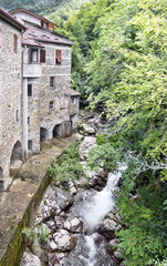 Fototapeta na wymiar Old mill and stream. Times gone by. Picturesque stone buildings.