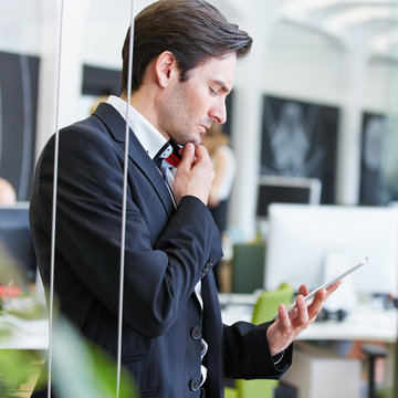 Mann im B&uuml;ro schaut auf Tablet Computer