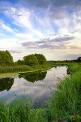 Fototapeta na wymiar Summer landscape with the sky and clouds reflecting in the river