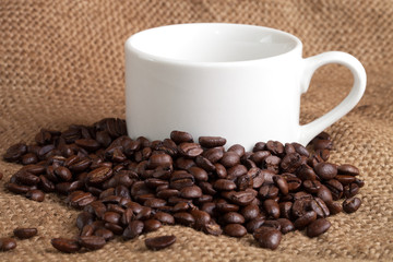 empty cup and roasted coffee beans on sackcloth