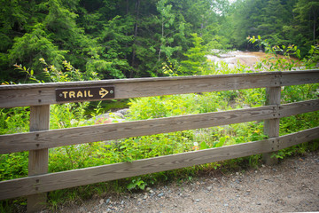 Fototapeta na wymiar Sign on fence pointing to trail