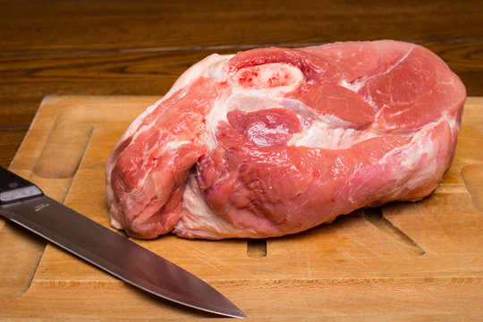 Raw cut of pork shoulder on board with knife