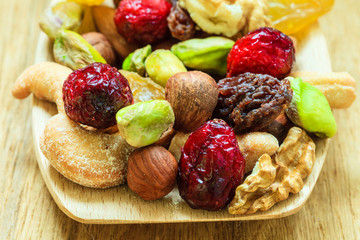 Varieties of dried fruits and nuts on wooden spoon.