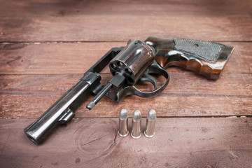 black revolver gun with bullets isolated on wooden background