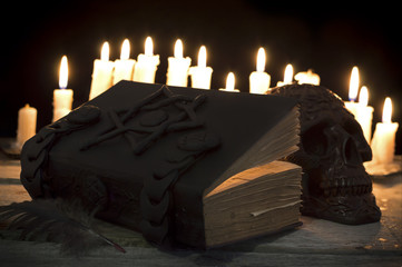 Magic book with candles and skull in the darkness