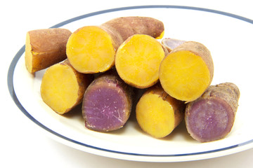 Boiled purple and yellow yams line up in dish on white backgroun
