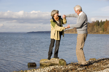 Ältere Paare,die Hand in Hand,Frau,die auf Baumstamm