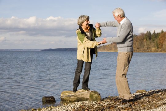 &Auml;ltere Paare,die Hand in Hand,Frau,die auf Baumstamm