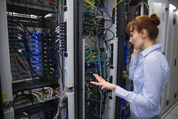 Technician talking on phone while analysing server © WavebreakMediaMicro
