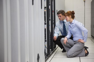 Team of technicians kneeling and looking at servers