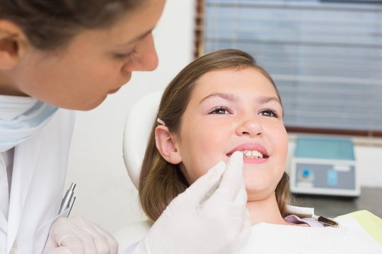 Pediatric dentist examining little girls teeth