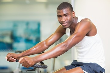Fototapeta na wymiar Portrait of man working out on exercise bike at gym