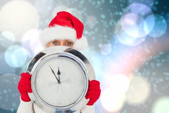 Composite image of festive woman holding clock