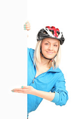 Female biker with helmet standing behind a panel