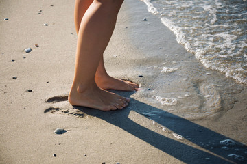 Feet of the girl walking in sea waves