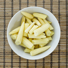 A side view of a dish of canned and sliced corn nuggets and ends
