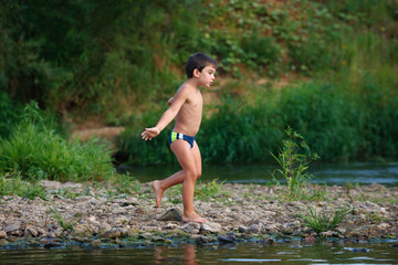 A boy is walking along the river bank