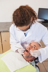 Fototapeta premium Dentist examining a patients teeth in the dentists chair