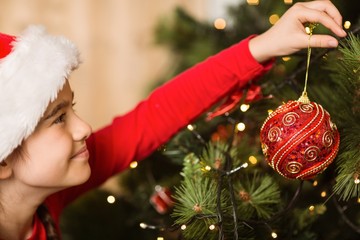 Festive little girl hanging a christmas decoration