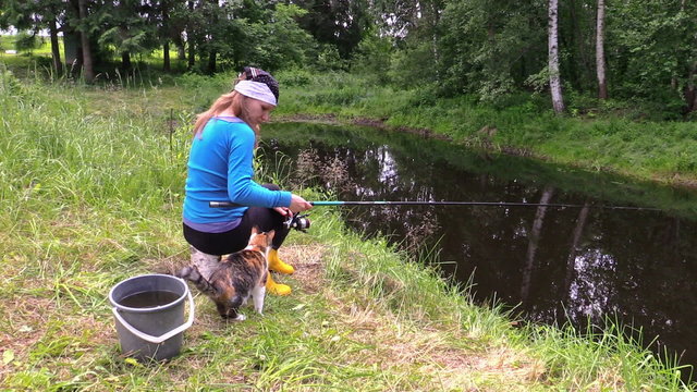 girl fishing at pond and play with little cat. Free time nature