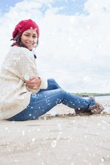 Smiling woman in warm clothing sitting at beach