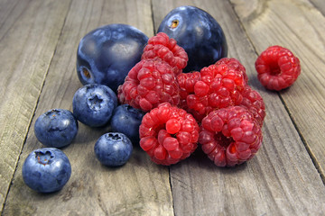 blueberries; raspberries and plums on wooden background