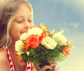 beautiful little girl smelling a bouquet of roses