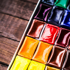 Watercolor paint and brush in white box on vintage wooden  backg