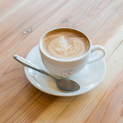 A cup of coffee with leaf pattern in a white cup