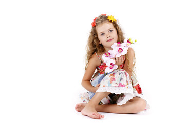 Beautiful little girl sitting on the floor and holding orchid
