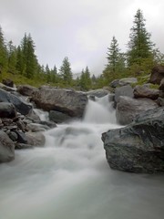 Cold rainy day. Stony stream bed of Alpine brook. 