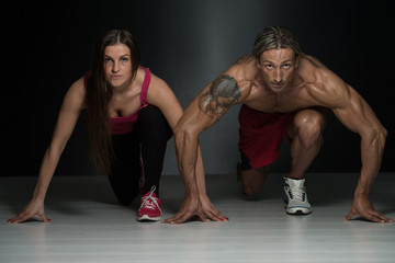 Fototapeta na wymiar Strong Muscular Couple Kneeling On The Floor