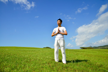 portrait of healthy young man doing yoga against sky