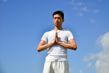 handsome man yoga routine against a blue sky