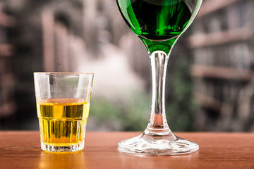 Glass with green cocktail and yellow shot