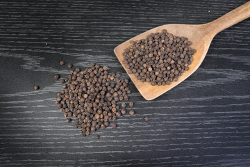 peppercorns in a spoon on rustic wooden table