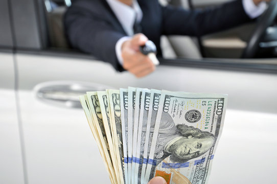 Businessman giving a car key exchanging with money 