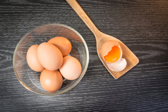 Group of brown eggs and yolk in wooden spoon