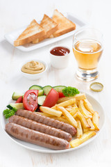 grilled sausages with French fries, vegetables and glass of beer