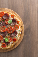 Italian pizza with salami and tomatoes on a wooden table