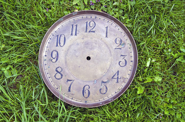ancient brass clock face on grass