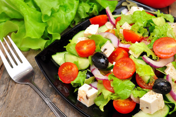 Greek salad and fork on a wooden table