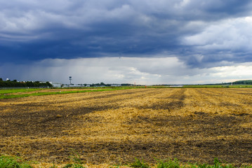Fototapeta premium Dramatic sky over field and airport
